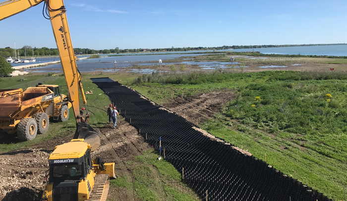 Image of geocell haul road being deployed over soft soils at Manitowoc Harbor. Excavator and loader seen on left.